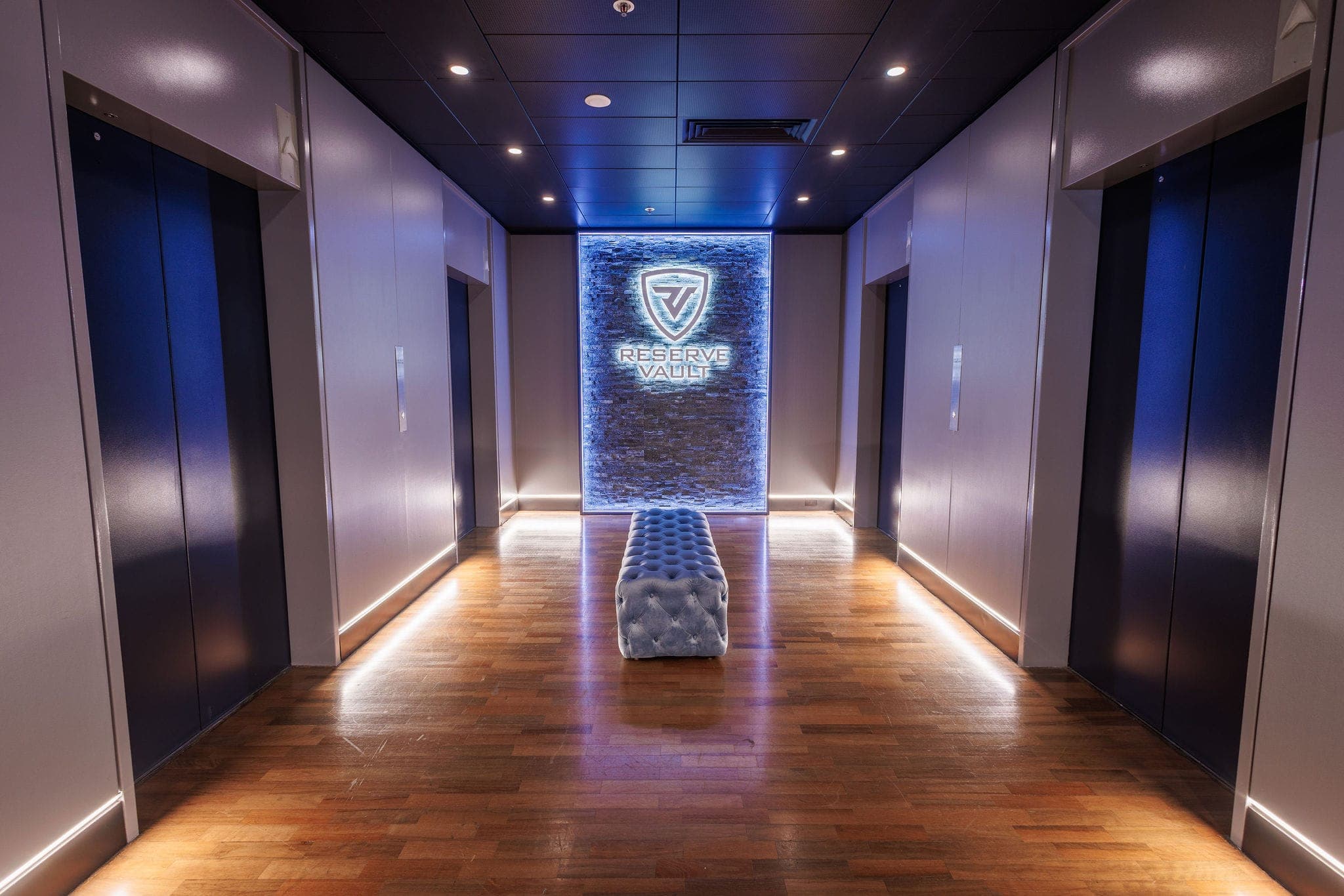 Reserve Vault lobby — a softly lit corridor leading to the illuminated stone logo wall