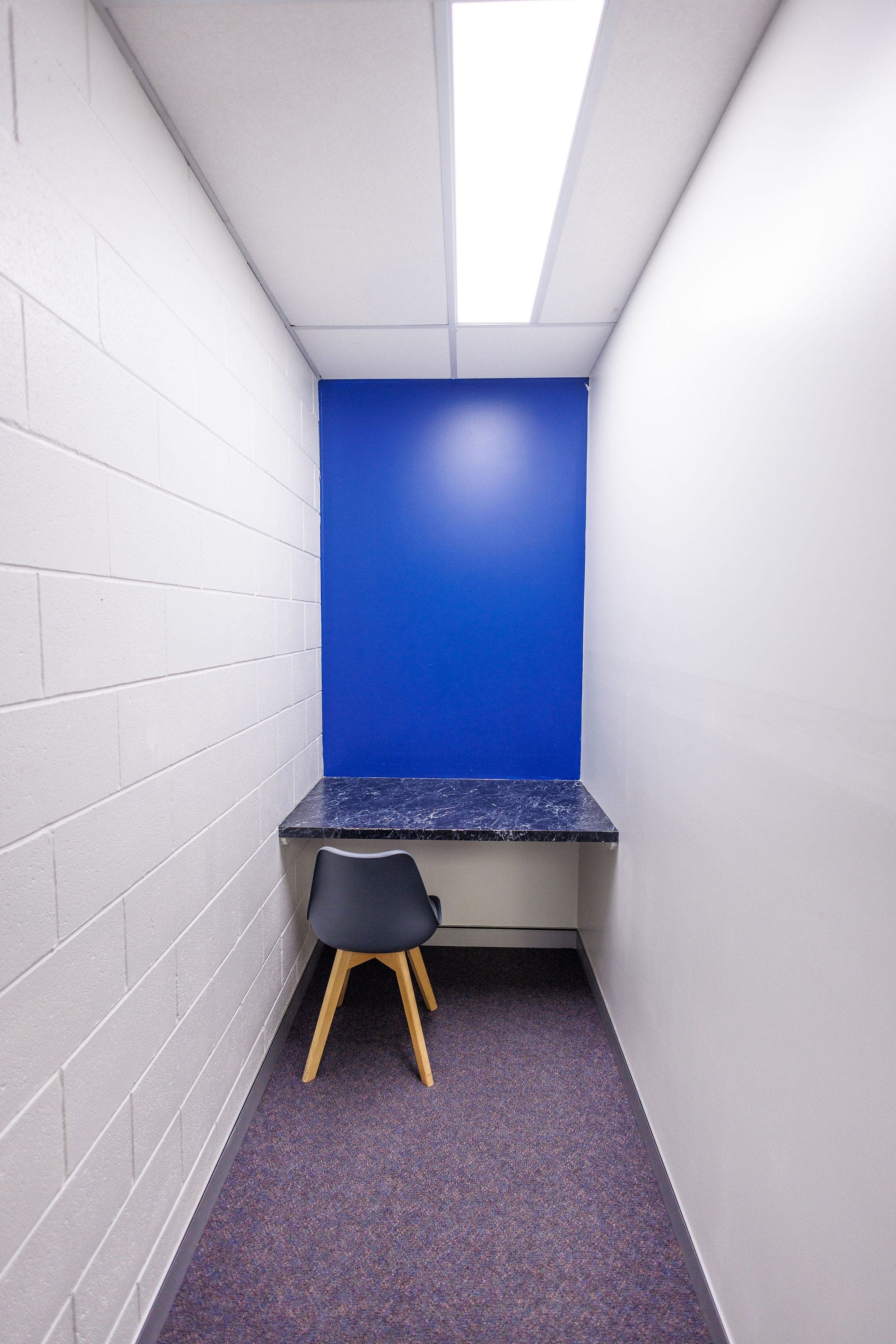 A small private viewing room with a single chair and a blue accent wall